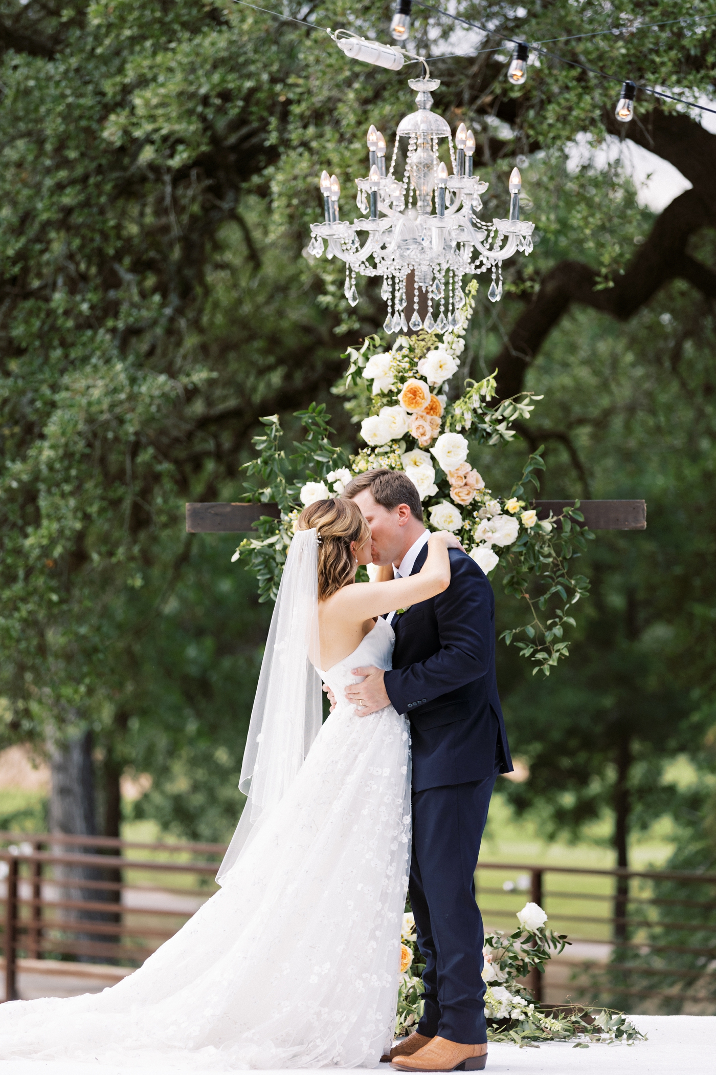 Bride and groom first kiss under a chandelier