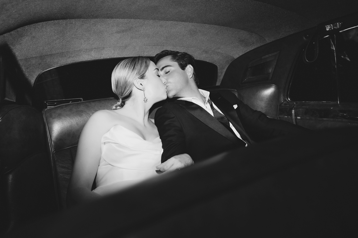 Bride and groom kissing in their getaway car