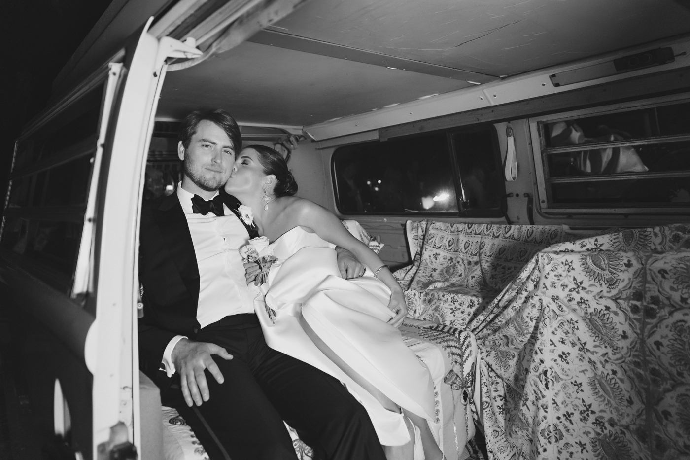 Couple sharing a kiss inside their VW bus getaway car