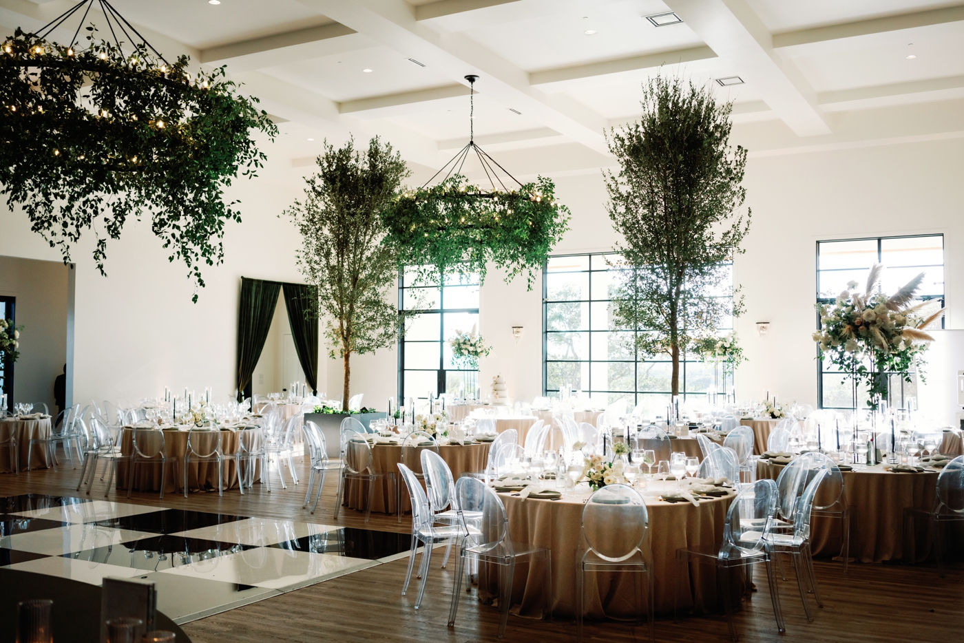 Indoor wedding reception with greenery chandeliers and trees