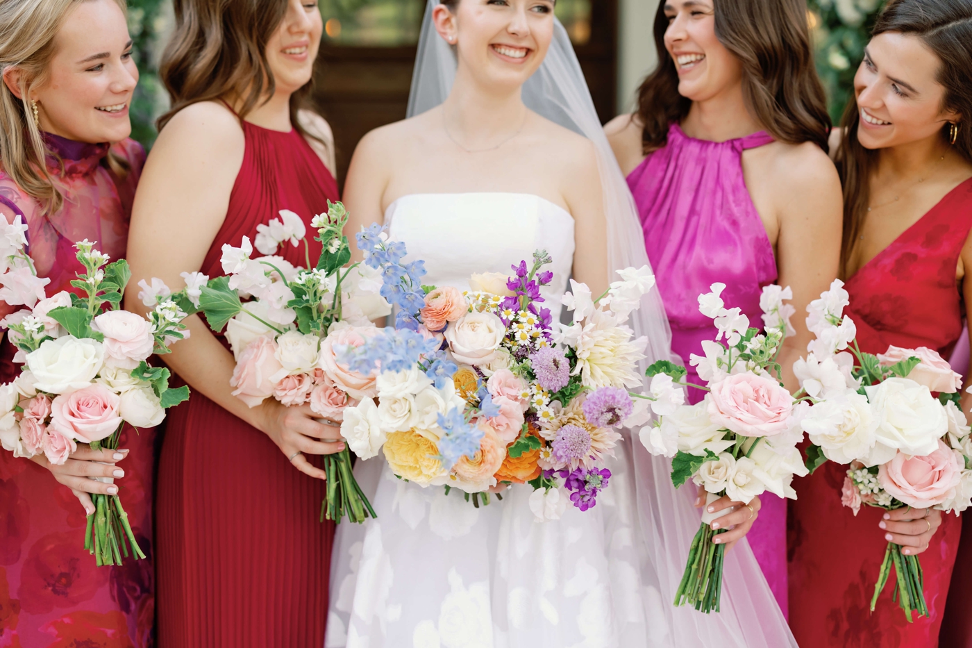 Pastel bridal and bridesmaids bouquet, with bridesmaids in bright pink and red dresses