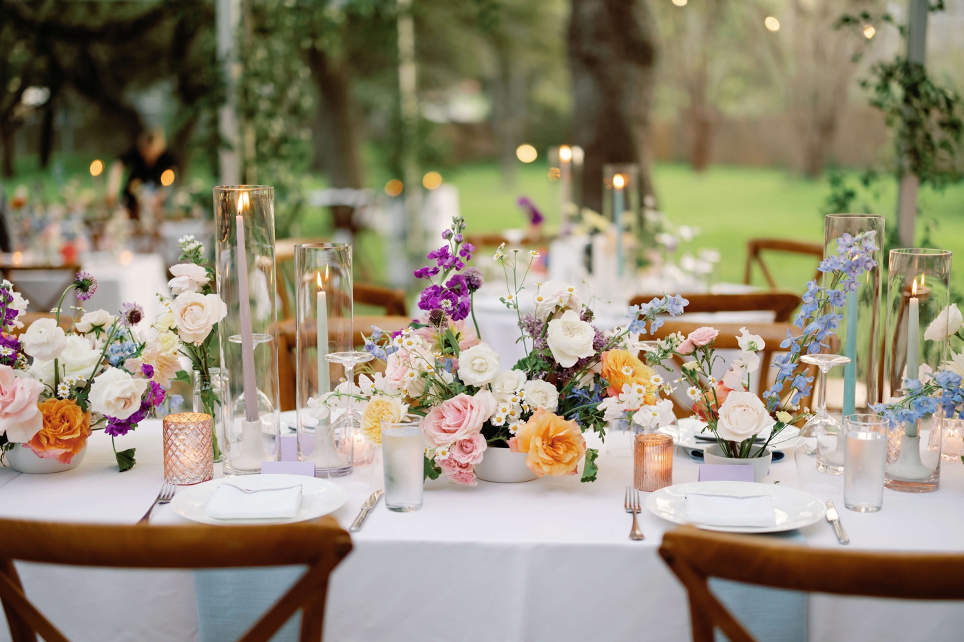 Pastel and ombre flower centerpieces at long tables under a clear tent