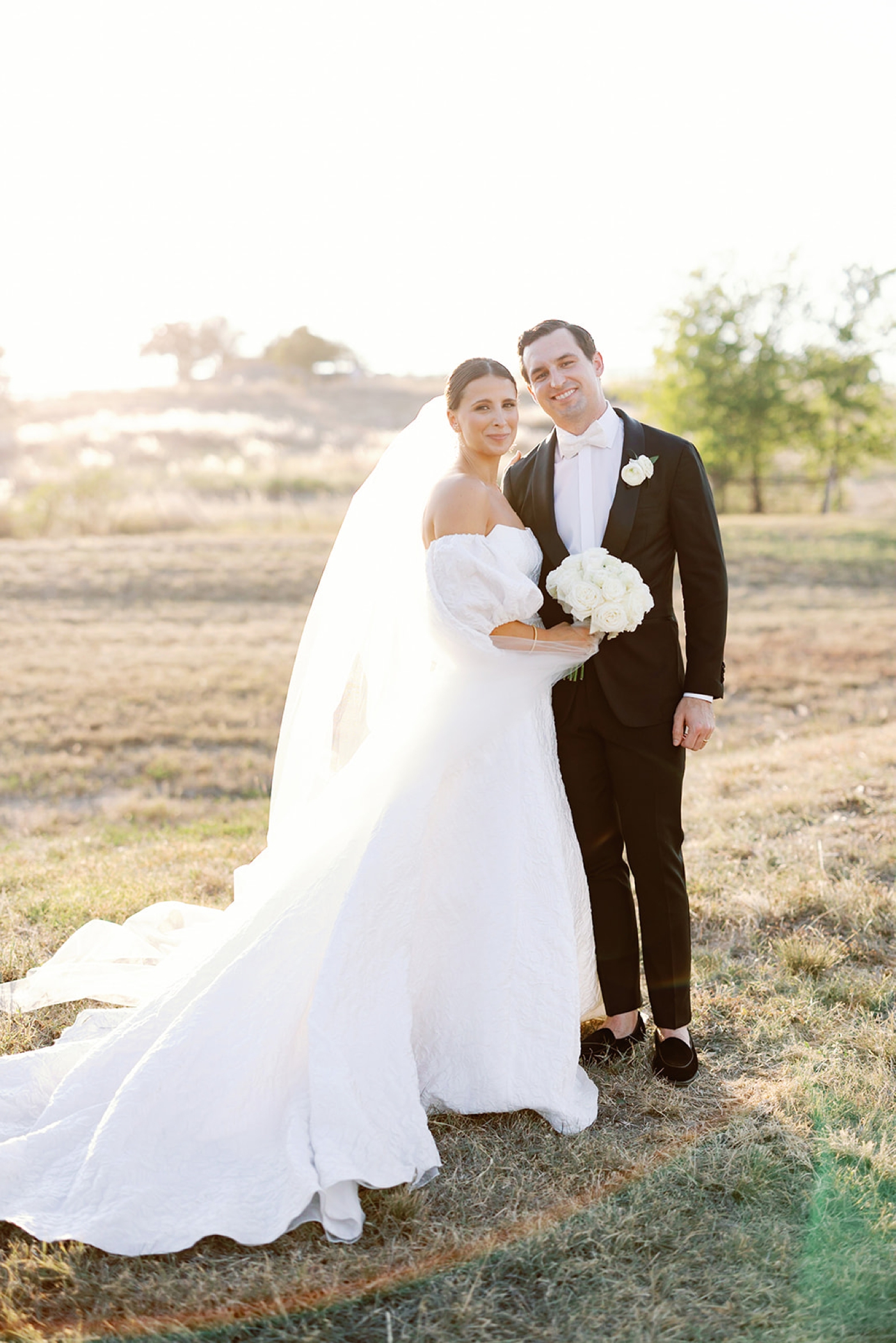 Sunset bride and groom pictures, with the groom in a classic tuxedo and the bride in an embroidered ballgown