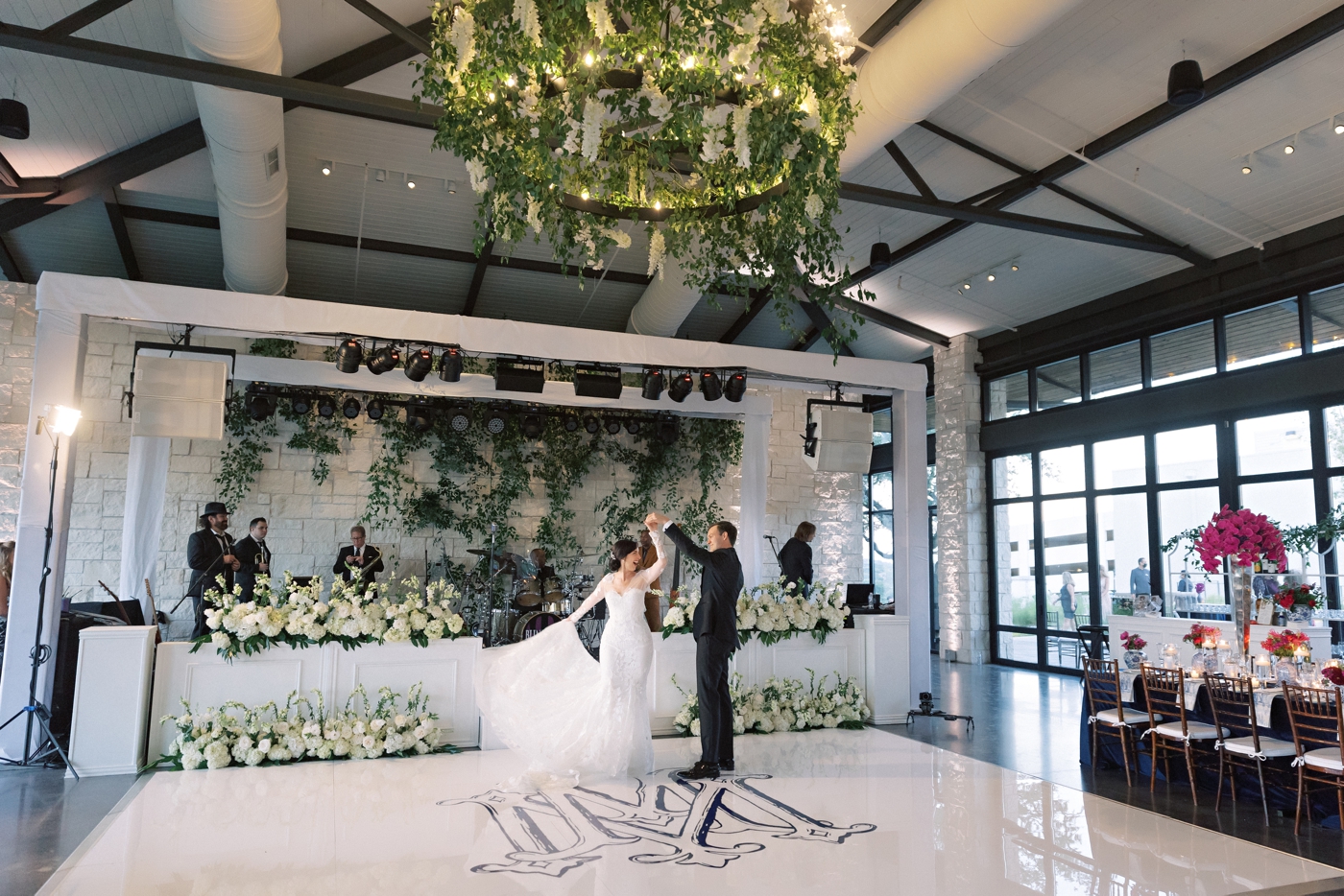 Bride and groom first look, with a monogrammed dance floor and hanging greenery on a chandelier 