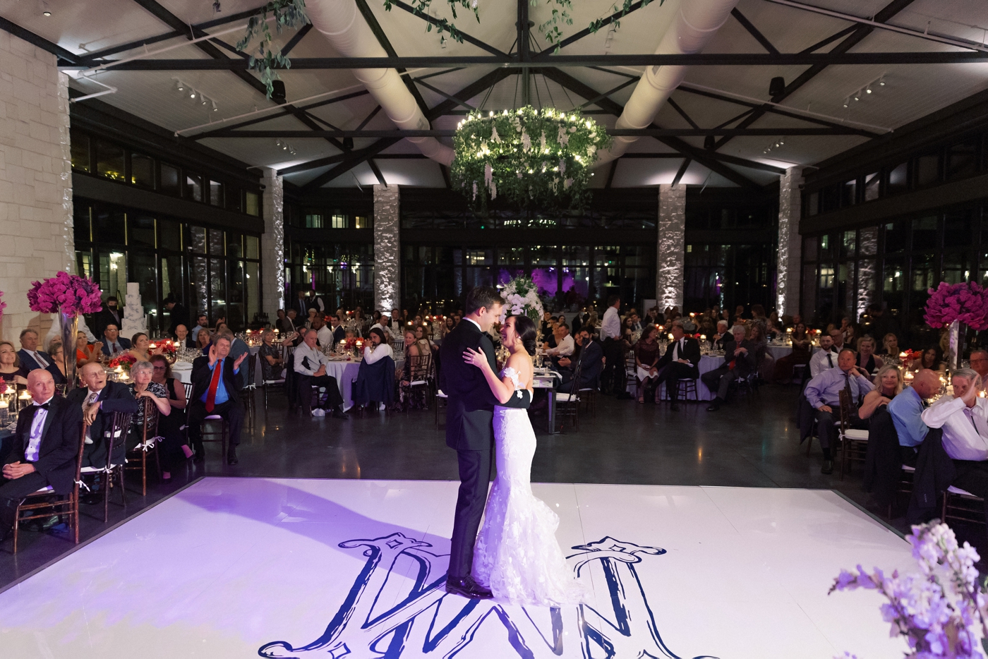 Bride and groom first look, with a monogrammed dance floor and hanging greenery on a chandelier 