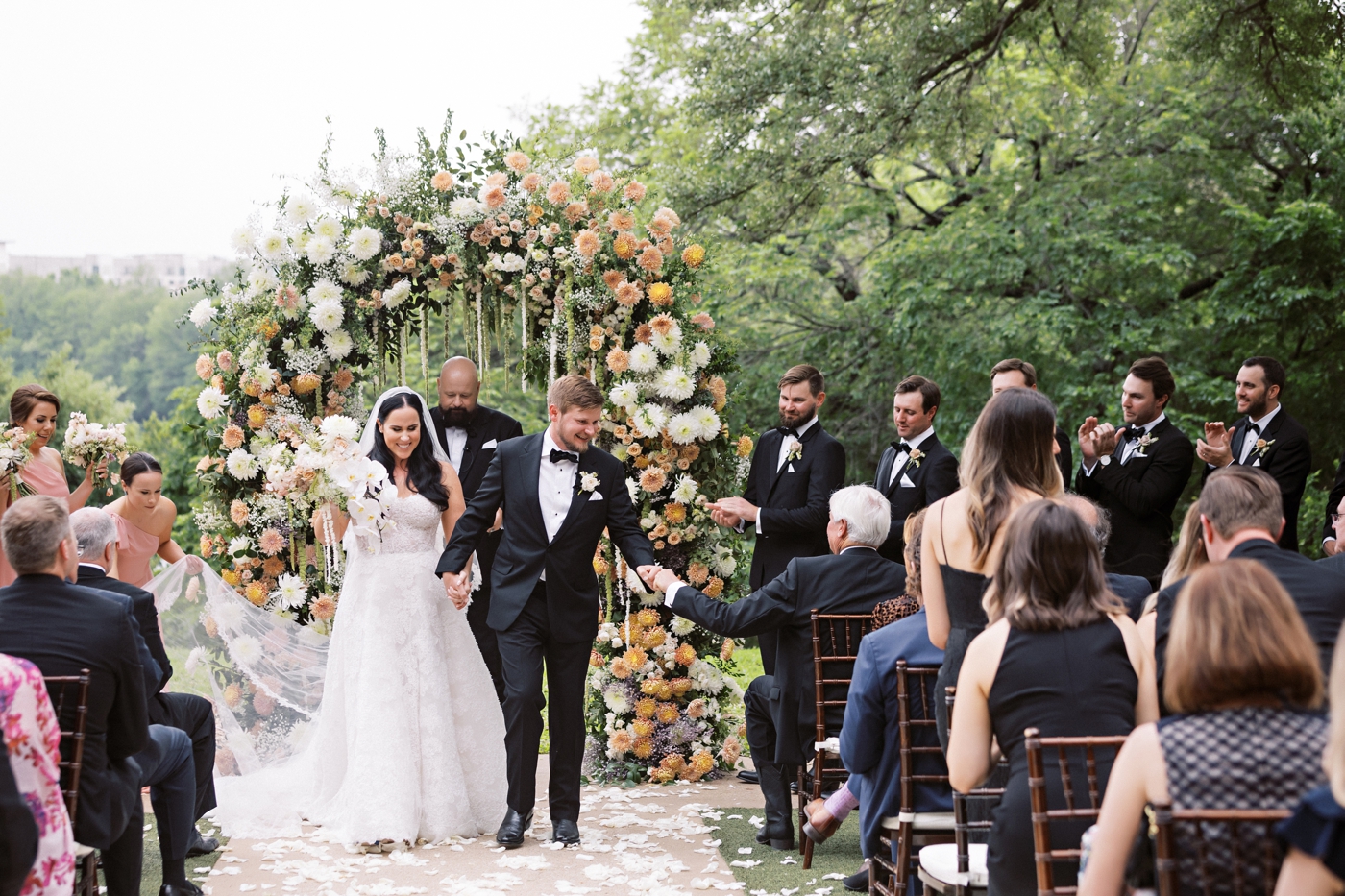 Groom and bride holding hands after their wedding ceremony, with the ceremony arch behind them 