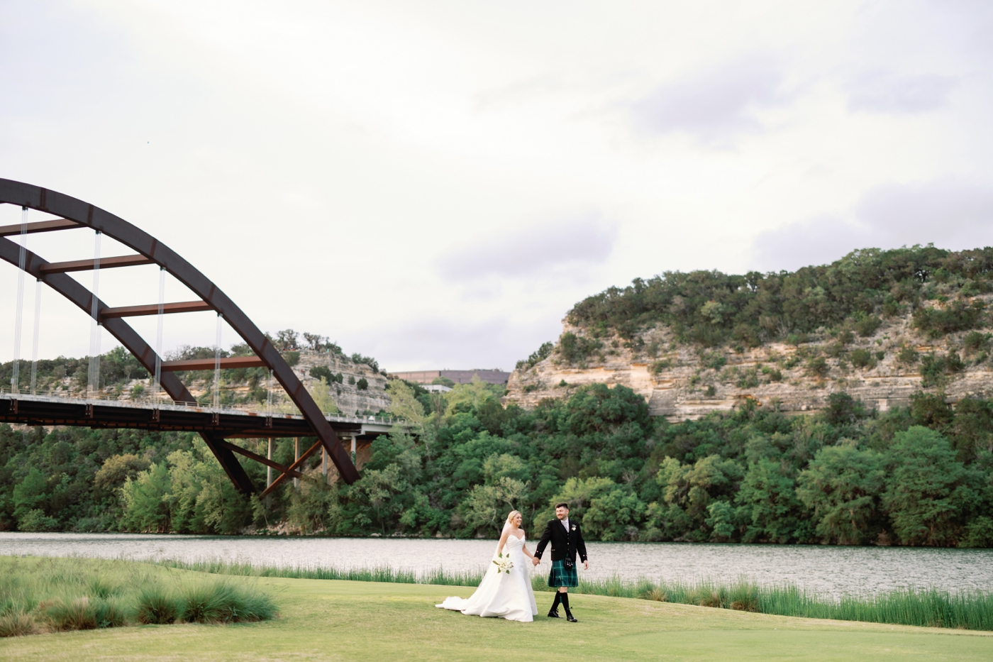 Bride and groom holding hands for wedding day pictures at the Austin Country Club, overlooking Lady Bird Lake