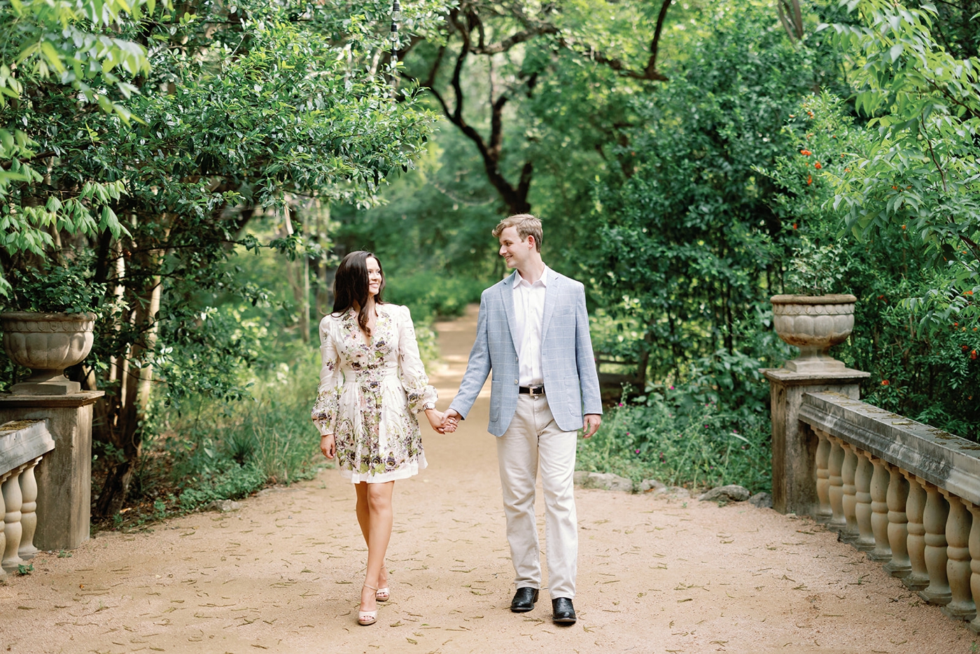 Bride wearing Zimmermann floral mini dress posing in the gardens at Laguna Gloria for her engagement session