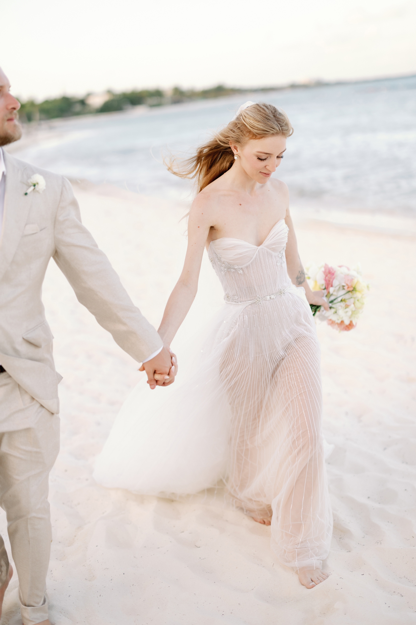 A bride and groom on the beach at Rosewood Mayakoba, for golden hour pictures after their wedding ceremony