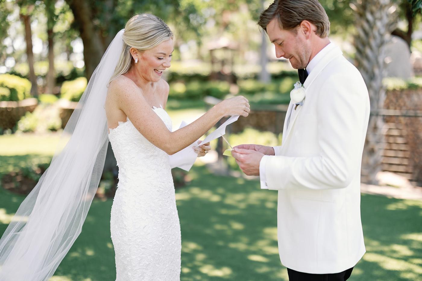 A bride and groom first look on the lawns of Horseshoe Bay Resort in Texas, with the bride in a fitted lace gown, the Take My Hand Gown by Sareh Nouri, and the groom in a white tuxedo