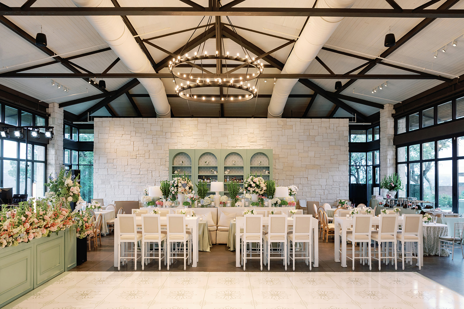 Lush spring floral arrangement with roses, hydrangeas, tulips, and greenery decorating the wedding reception at Omni Barton Creek Resort, with a mix of square, round, and bar seating around a custom dancefloor